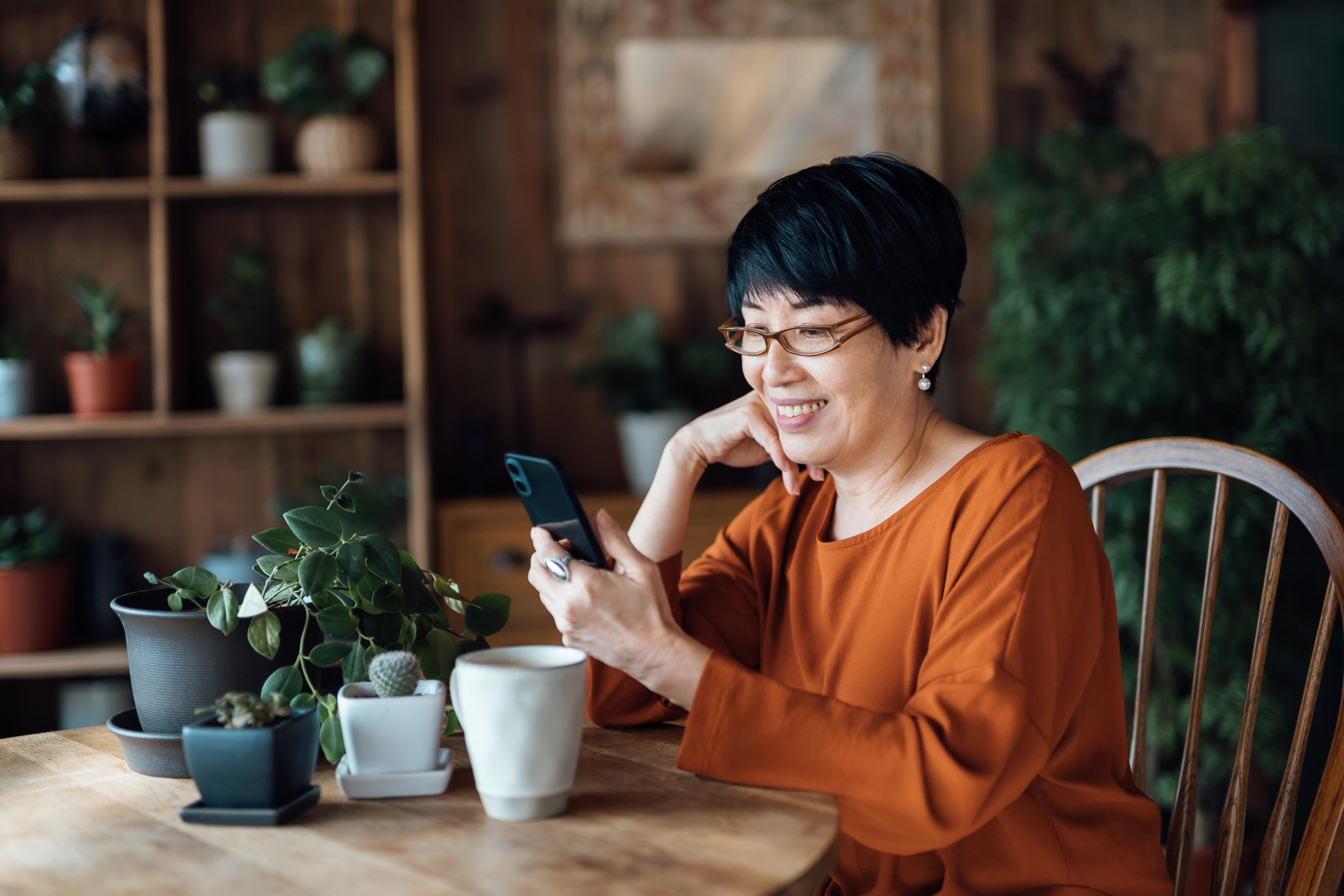 Woman on the phone while at dinner table.