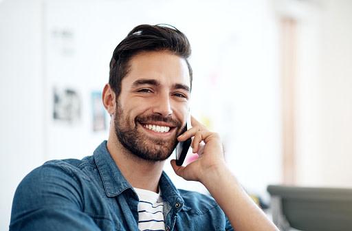 Two friends at a table using mobile payments to send each other money.