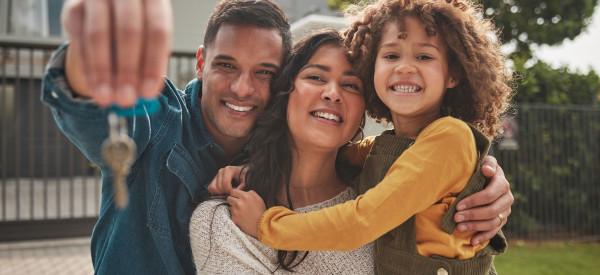 A family hugging, looking at a pair of keys.